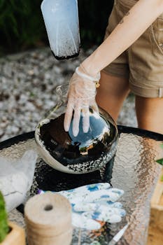 A gardener making a terrarium with soil and tools on a glass table.